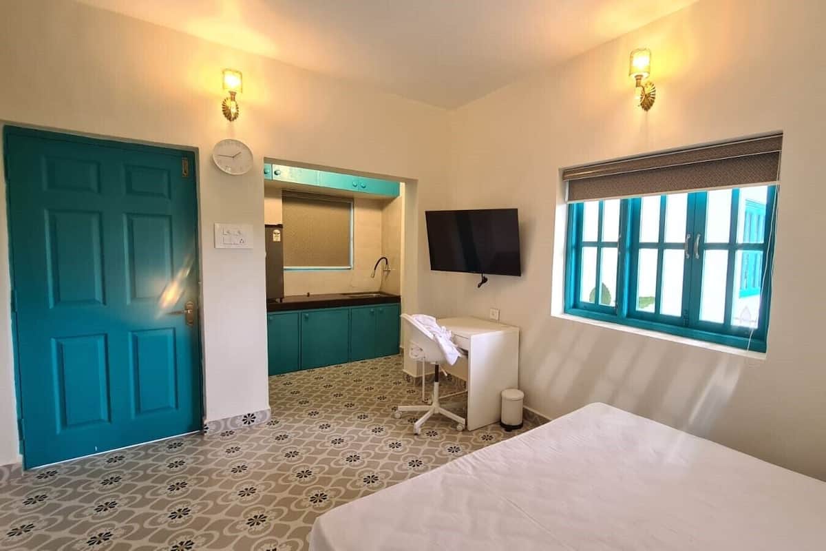 A hotel room with a bed, a desk, a chair, a sink, and a window.