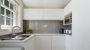 A modern kitchen with white cabinetry, a stainless steel sink, a microwave, and a toaster. - Ridgedale Cottage, Bayview. The perfect romantic retreat! (Bayview)