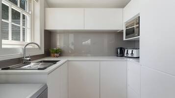 Eine moderne Küche mit weißen Schränken, einer Edelstahl-Spüle, einer Mikrowelle und einem Toaster.