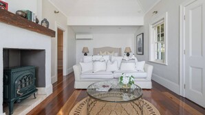 A living room with a white sofa, a glass coffee table, and a fireplace. - Ridgedale Cottage, Bayview. The perfect romantic retreat! (Bayview)