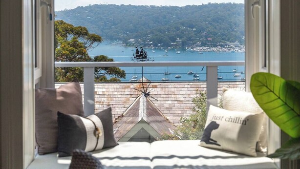 A bay window with a view of a harbor, a cushioned bench, and a pillow with the text "just chillin'". - Ridgedale Cottage, Bayview. The perfect romantic retreat! (Bayview)