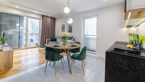 A modern kitchen with a black sink, wooden cabinets, and a dining area with a round table and green chairs.