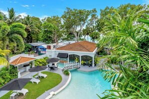 A resort with a swimming pool, lounge chairs, umbrellas, and lush greenery. - Alassio 303/1 | 1 Bedroom Apartment (Palm Cove)