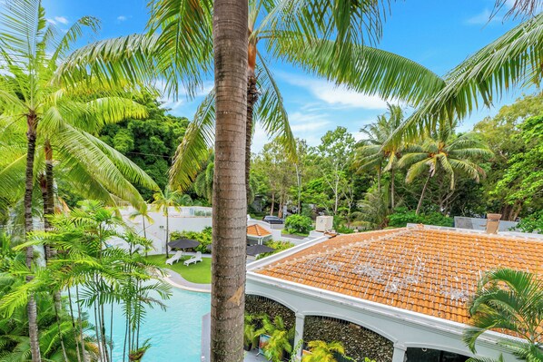 Un resort con piscina rodeada de palmeras y un edificio de techo de tejas.