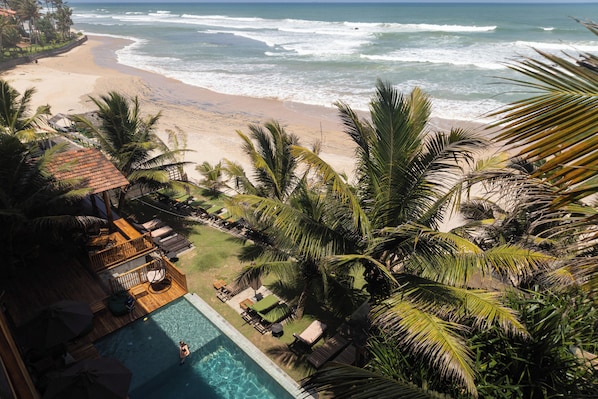 Un resort con piscina, vista a la playa y palmeras.