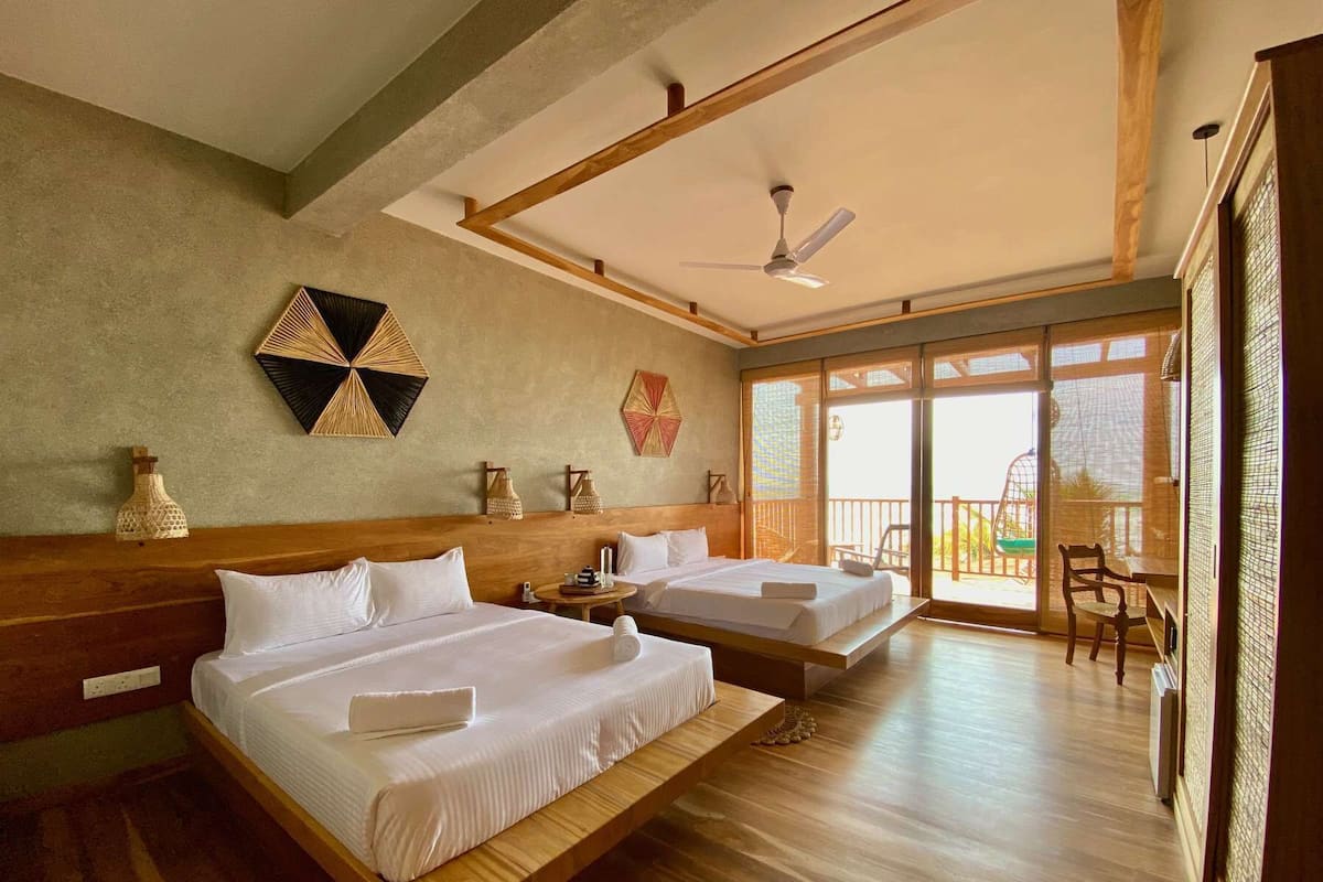 A hotel room with two beds, a ceiling fan, and a balcony with a view.