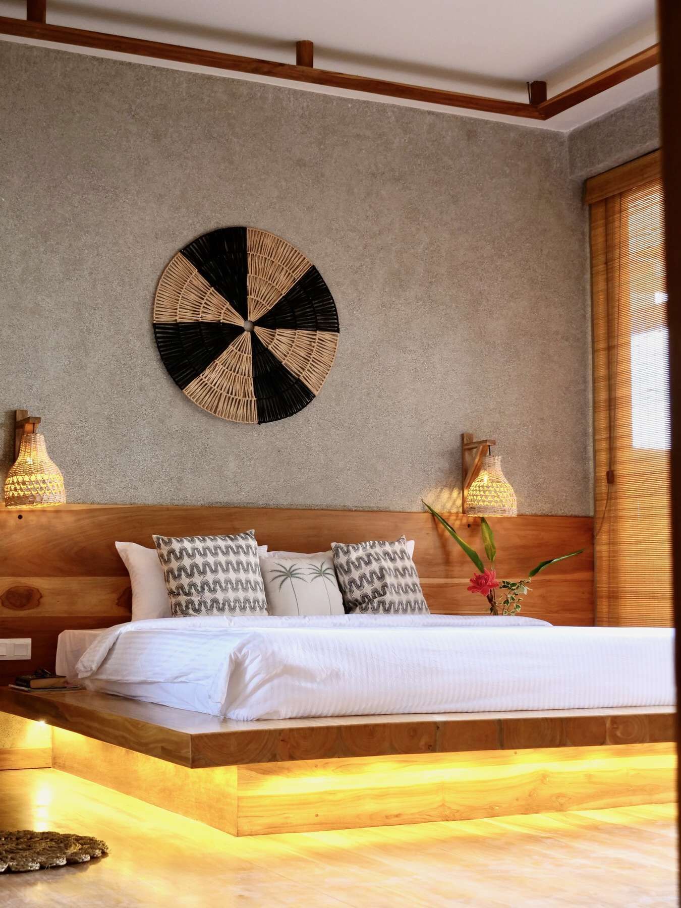 A bedroom with a wooden headboard, a round wall decoration, and two bedside lamps.