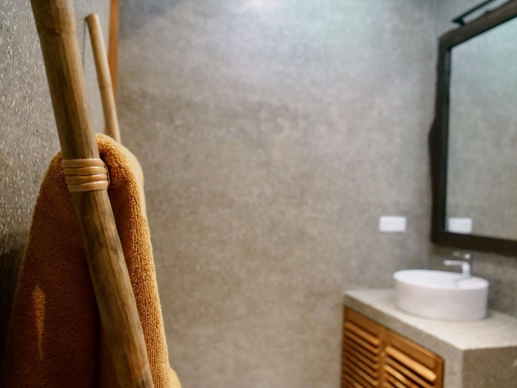 A bathroom with a wooden towel rack, a sink, and a mirror.