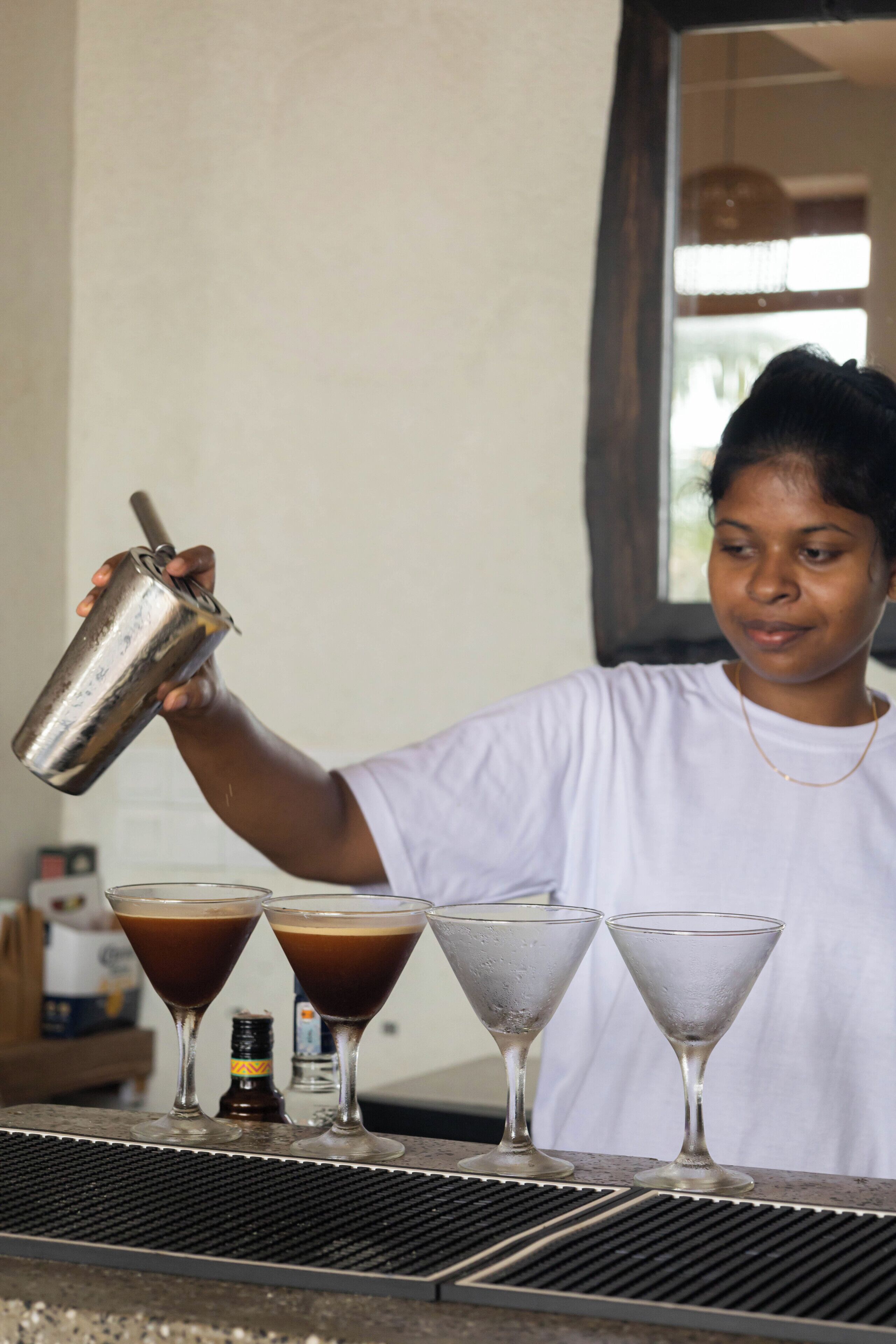 A person pouring a drink into a martini glass.