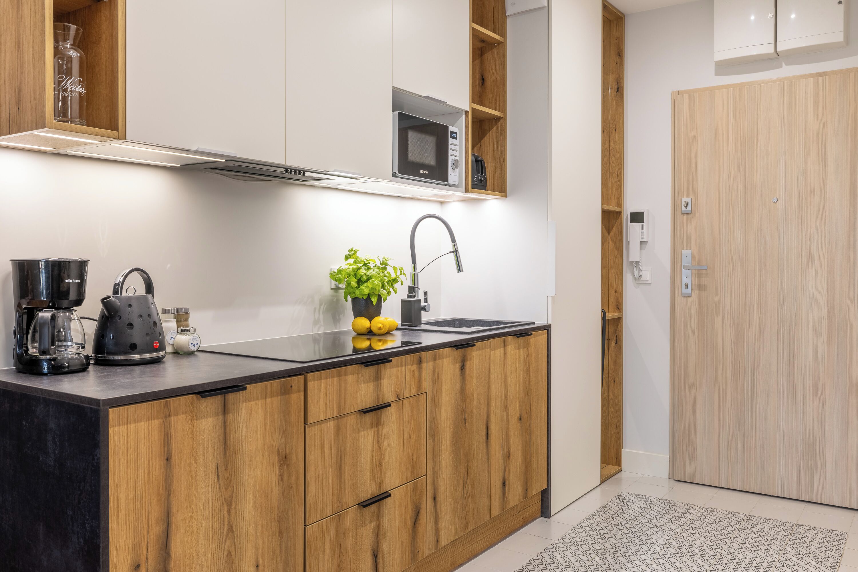 A modern kitchen with wooden cabinets, a black countertop, a microwave, and a coffee maker.