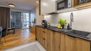 A modern kitchen with wooden cabinets, a black countertop, and a built-in microwave.