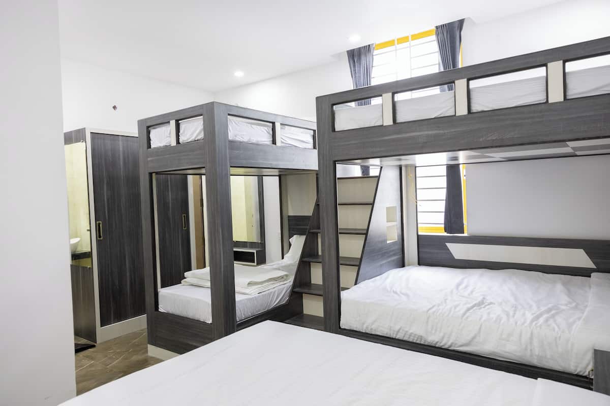 A bunk bed room with a mirror, a wardrobe, and a window with curtains.