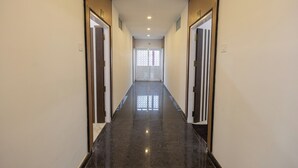 A hallway with a polished floor, doors on both sides, and a window at the end. - Hotel Kurunjii Residency (Yercaud)