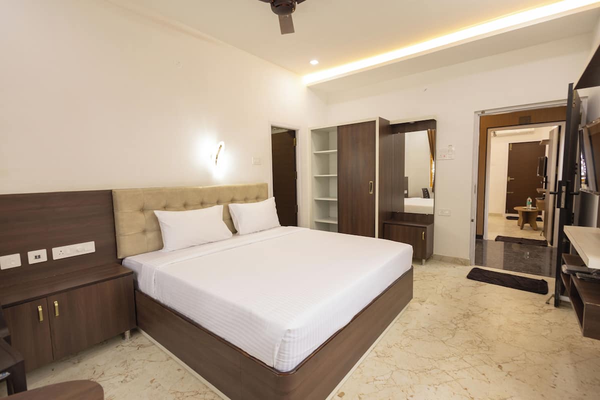 A modern hotel room with a large bed, wooden headboard, built-in wardrobe, and a mirror.