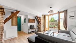 Un salon moderne avec un canapé, un téléviseur et un mur en pierre.