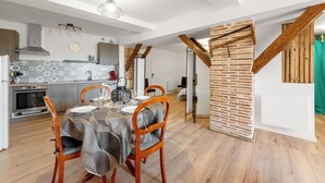Une cuisine moderne avec un coin repas, caractérisée par des murs en briques apparentes, des poutres en bois et un pare-feu en carreaux.