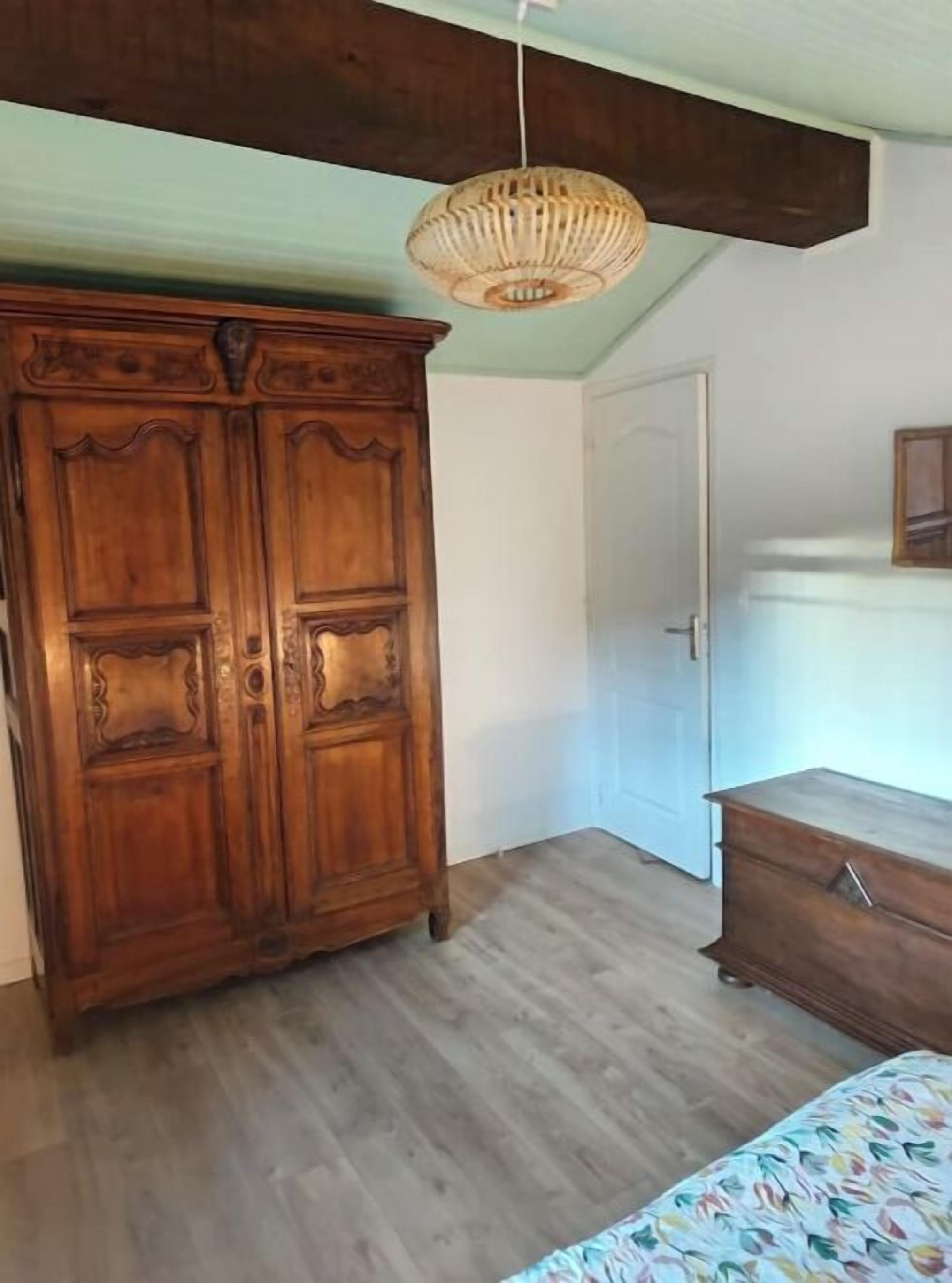 Een kamer met een grote houten garderobe, een klein dressoir en een hanglamp.