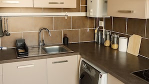 A modern kitchen with beige cabinets, a dishwasher, a sink, and a stove. - Charming apartment with terrace (Le Cannet)
