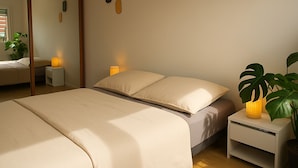 A bedroom with a bed, bedside tables, a mirror, and a potted plant. - Charming apartment with terrace (Le Cannet)