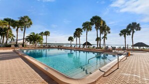 A rectangular swimming pool with a tiled deck, surrounded by palm trees and lounge chairs. - The Riverside Club - B204 (Marco Island)