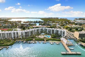 A marina with boats docked, a pool area, and a residential building complex with multiple floors. - The Riverside Club - B204 (Marco Island)