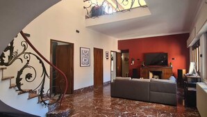 Uma sala de estar ampla com uma parede vermelha de destaque, um sofá grande e uma lareira.