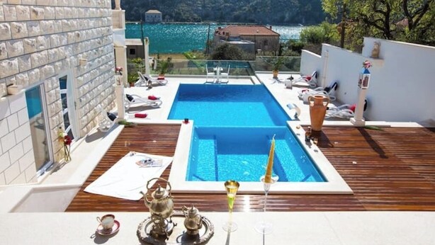 Ein Pool auf dem Dach mit klarem, blauem Wasser, umgeben von einer Holzterrasse und Liegestühlen.