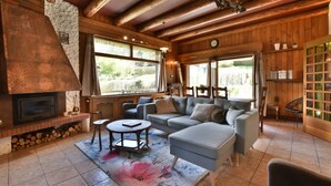 A cozy living room with a fireplace, wooden beams, a sofa, and a coffee table. - Authentic chalet at the foot of the Mont Blanc range (Les Houches)