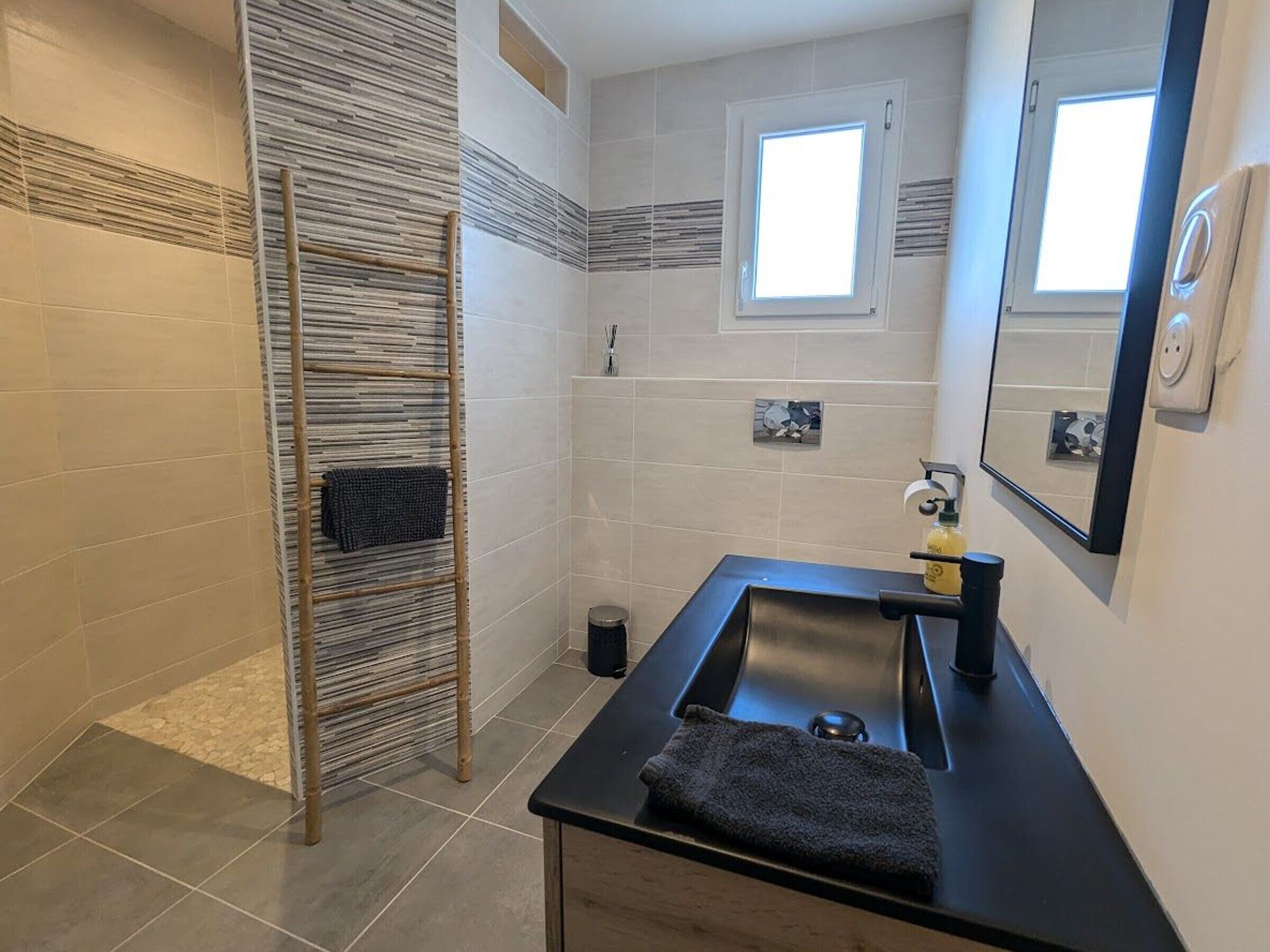 A bathroom with a glass sink, a mirror, a towel rack, and a window.