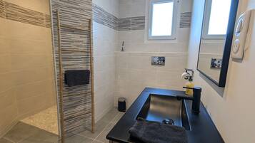 A bathroom with a glass sink, a mirror, a towel rack, and a window.