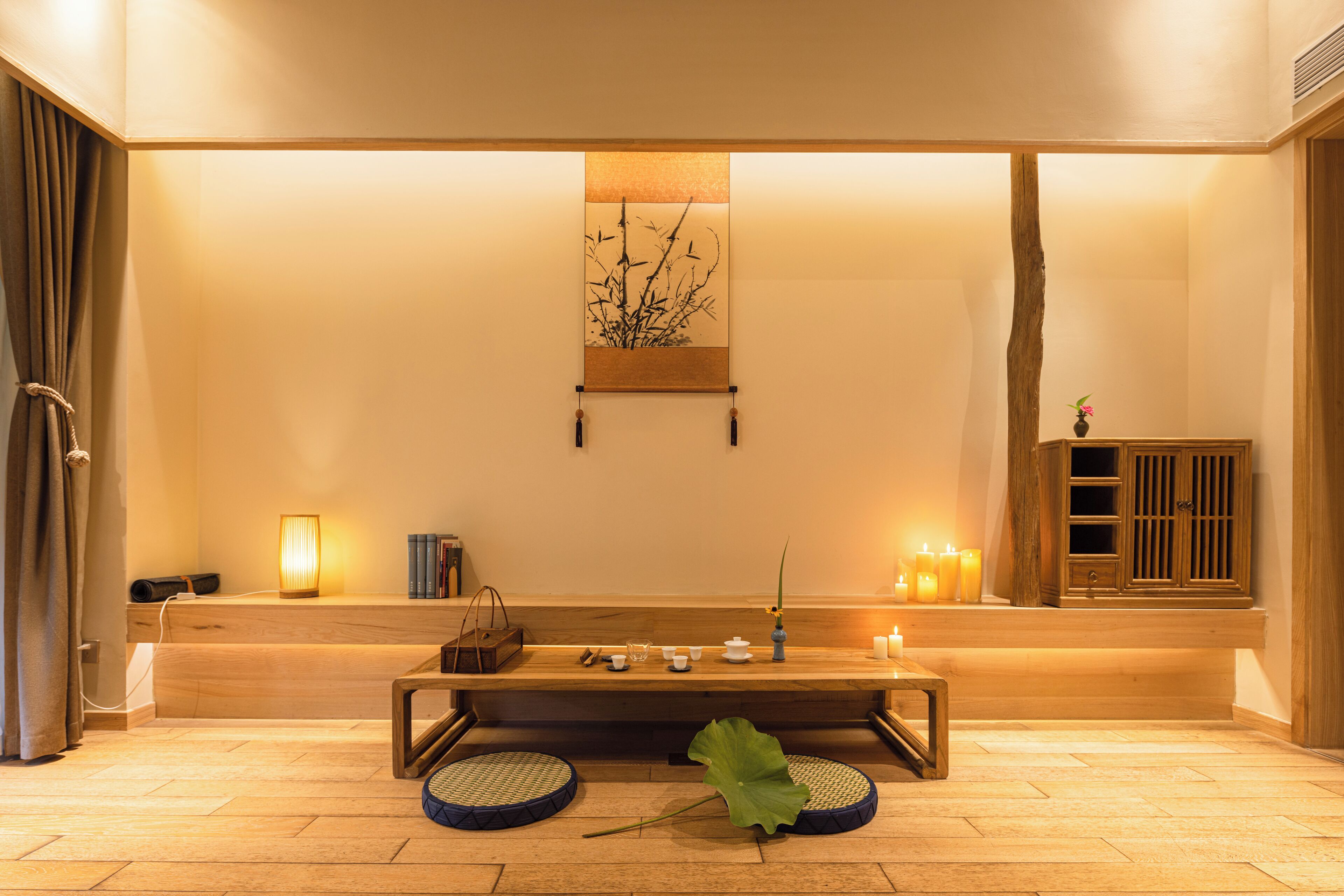 Una habitación tranquila con un banco de madera, una obra de arte en la pared, velas y un mueble bajo.