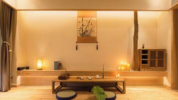 Una habitación tranquila con un banco de madera, una obra de arte en la pared, velas y un mueble bajo.