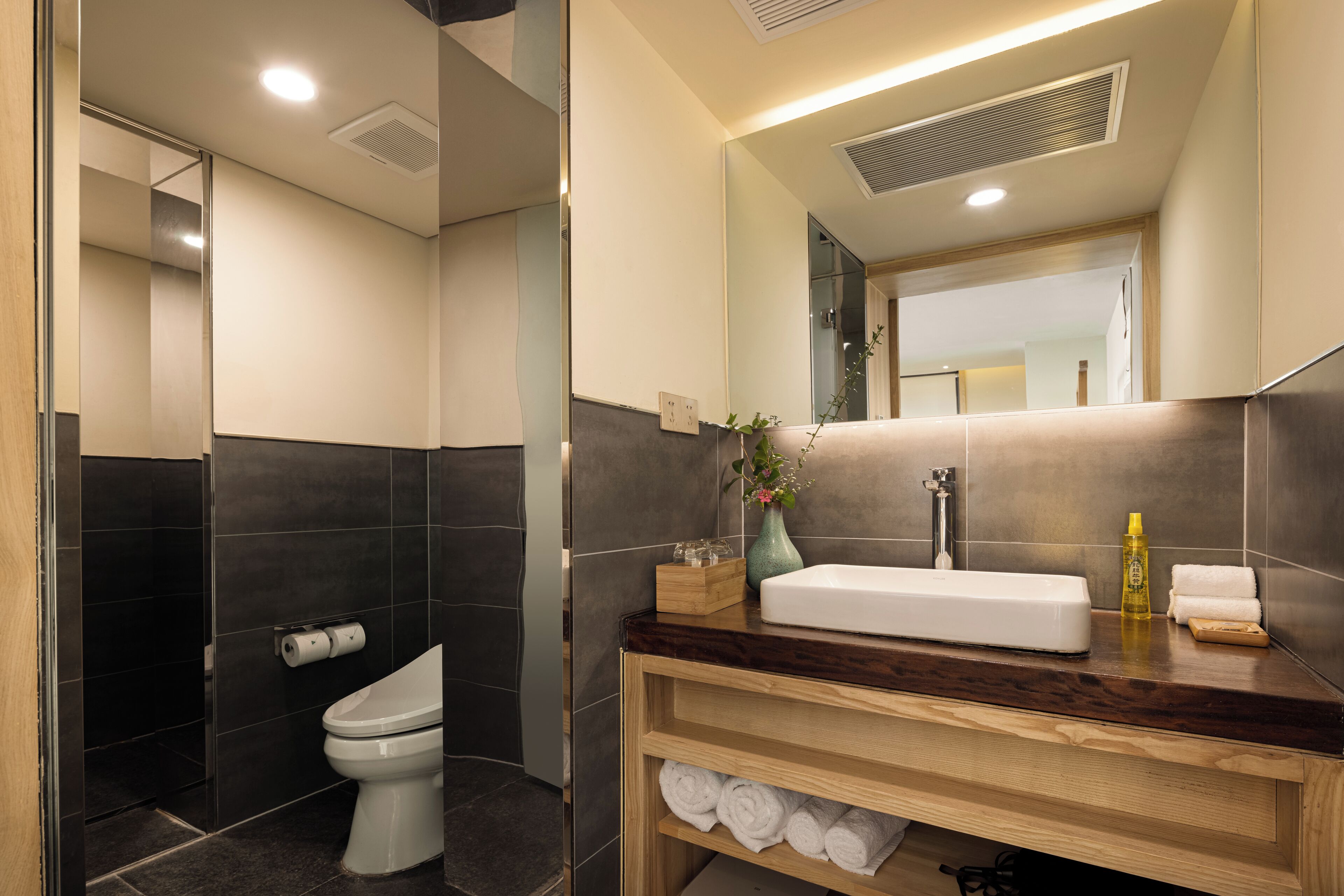 A modern bathroom with a toilet, sink, and mirror.