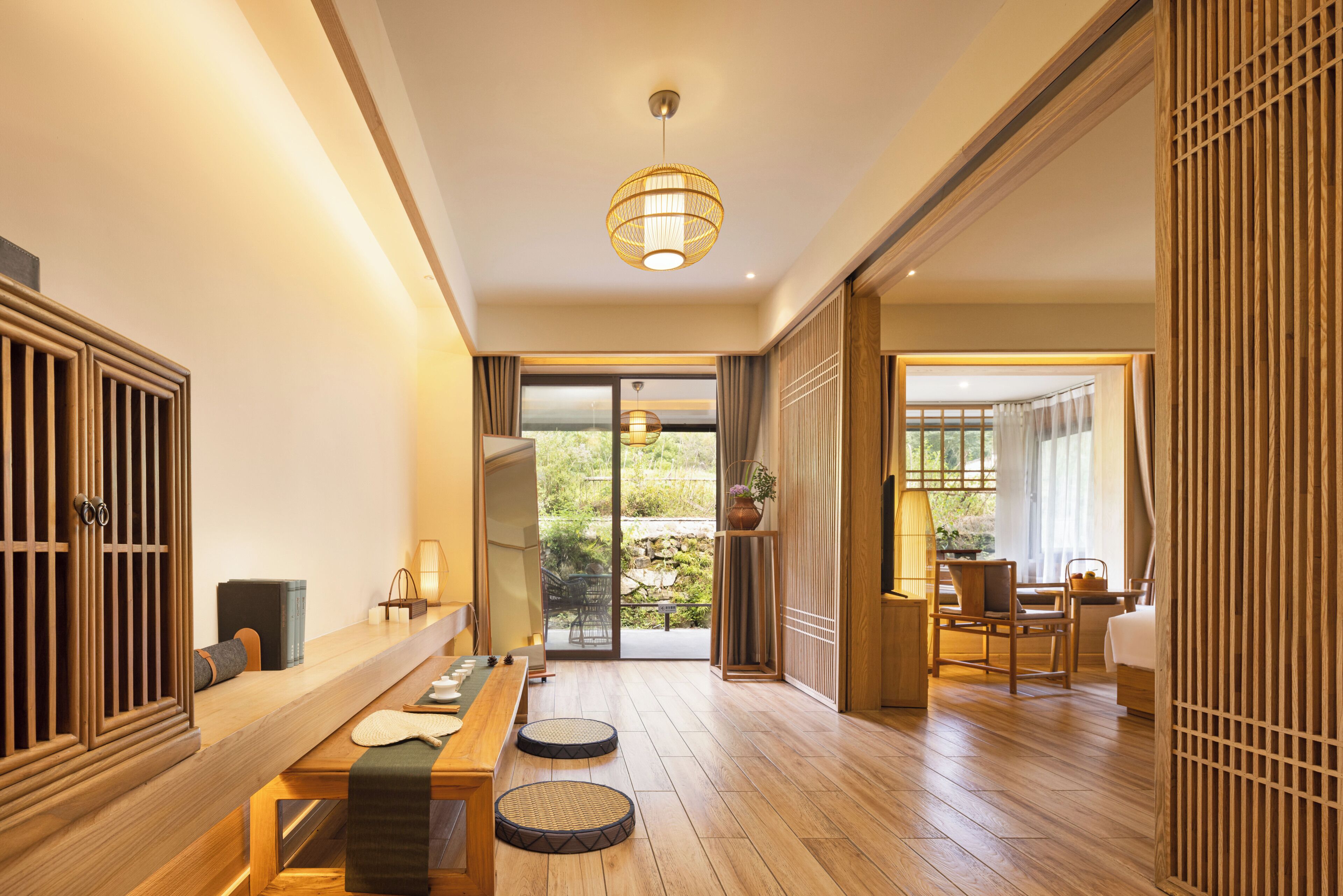 Una habitación tradicional japonesa con suelo de tatami, una mesa baja y puertas correderas que dan a un jardín exterior.