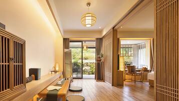 Una habitación tradicional japonesa con suelo de tatami, una mesa baja y puertas correderas que dan a un jardín exterior.