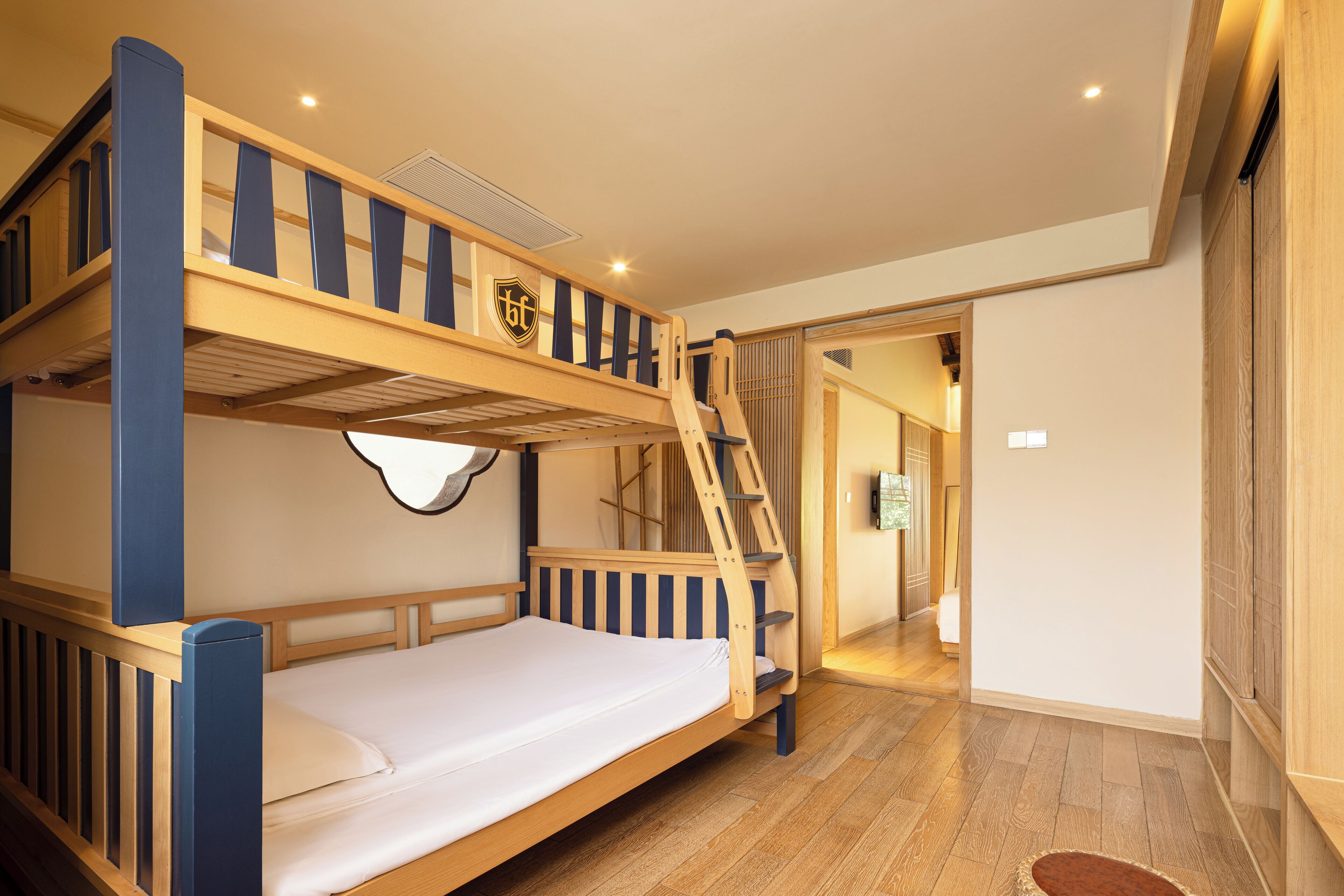 A bunk bed room with a wooden ladder and a small window.