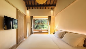 A bedroom with a large bed, a TV mounted on the wall, a window with a view of greenery, and a wooden ceiling. - Tachuan Resort (Huangshan)