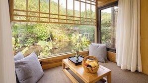 A room with a large window, wooden furniture, and a view of greenery. - Tachuan Resort (Huangshan)