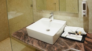 A modern bathroom with a glass-enclosed shower, a white sink, and a large mirror. -  The Krati Resort (Bareilly)