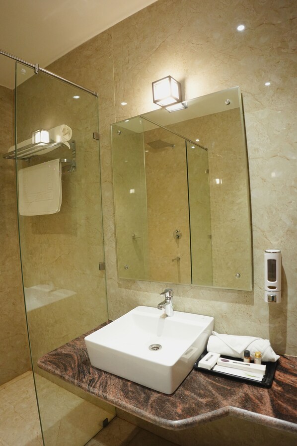 Un bagno moderno con doccia vetro, lavandino bianco e un grande specchio.
