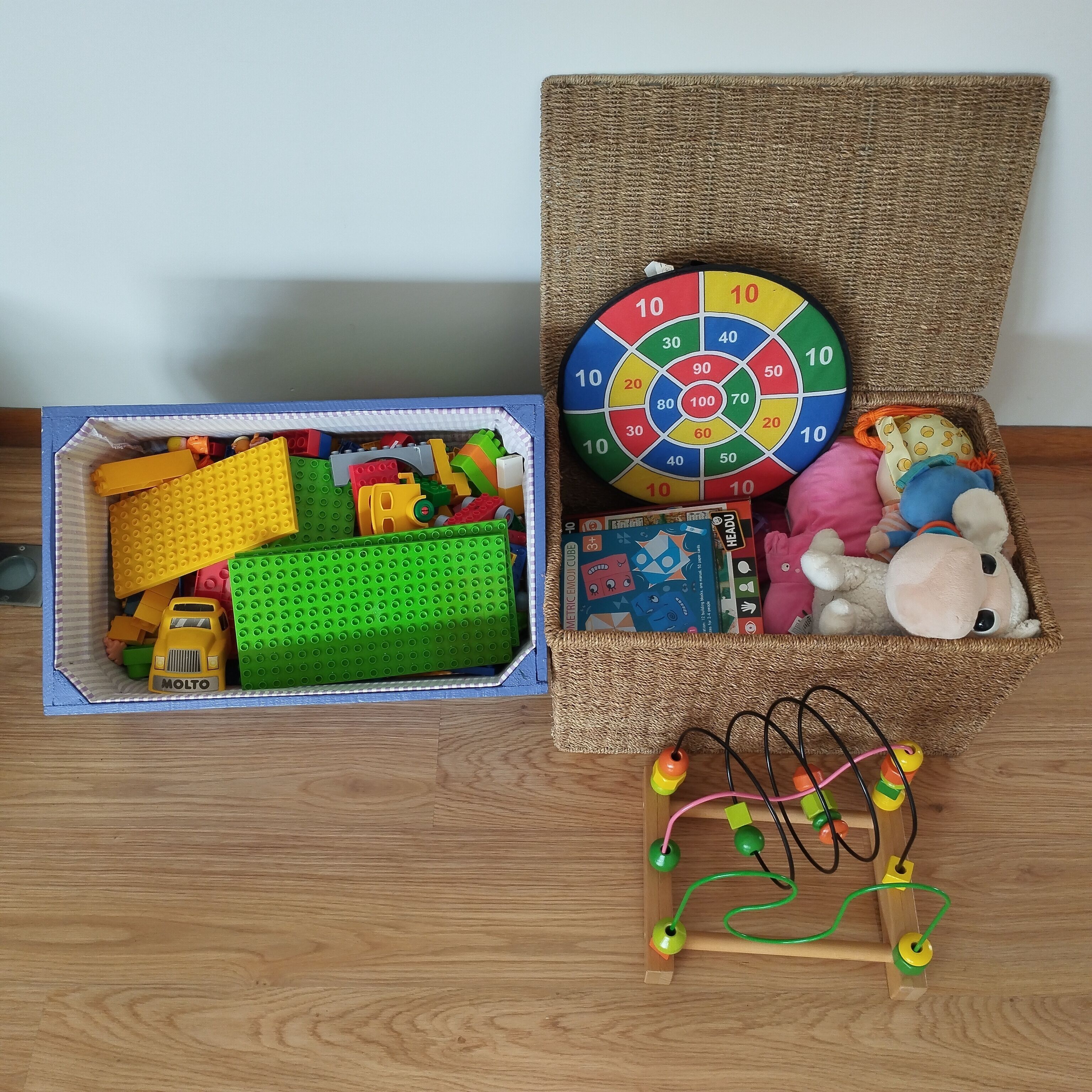 Une boîte de rangement contenant divers jouets, notamment une voiture jouet, des blocs de construction et un train jouet.