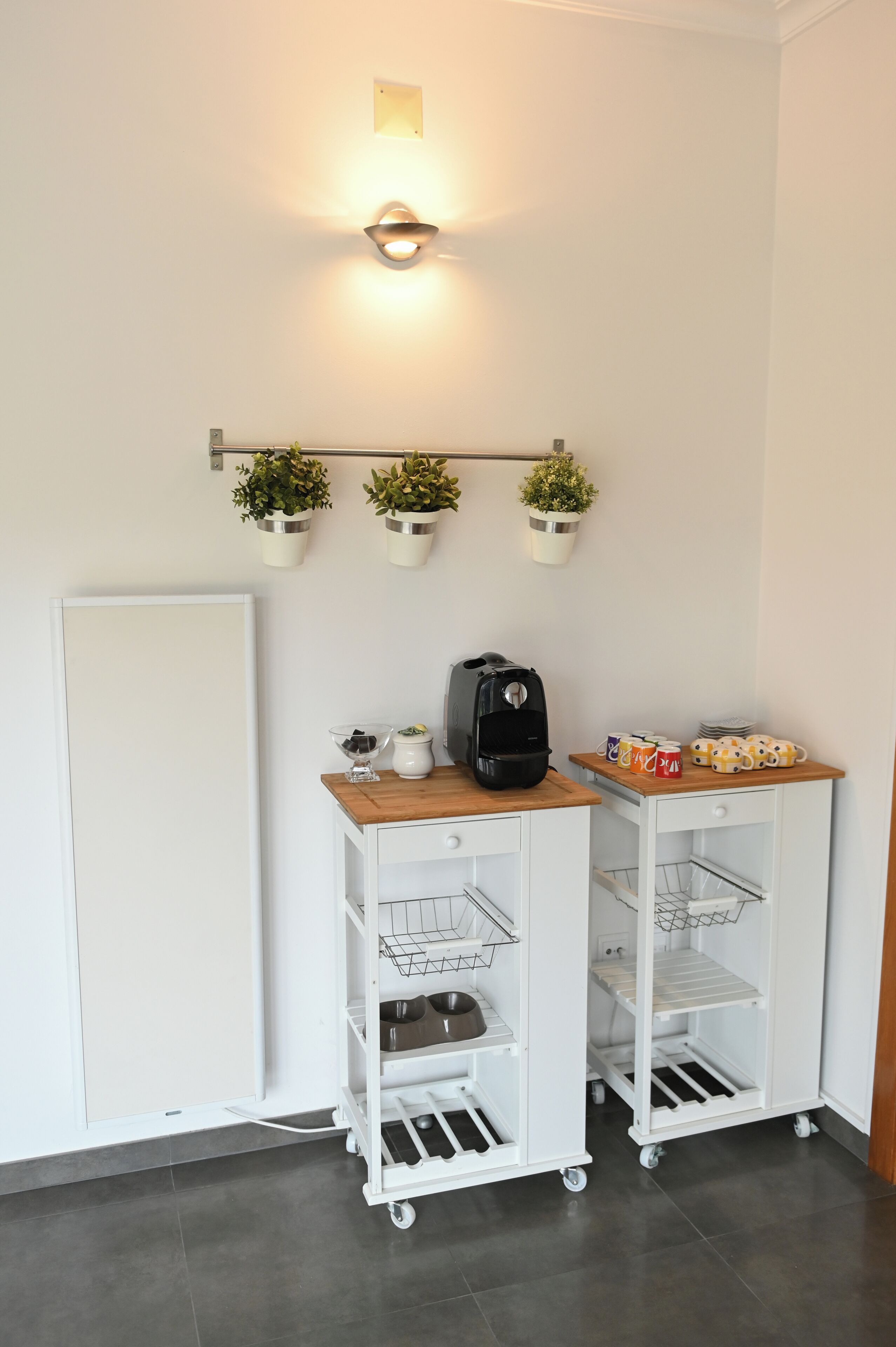 Un chariot blanc doté d’étagères, une machine à café et des tasses sur un comptoir.