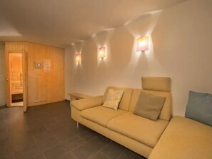 A room with a sofa, a wooden cabinet, and wall-mounted lights.