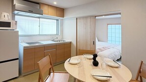 Ein kompaktes Hotelzimmer mit Küchenzeile, einem Essbereich mit rundem Tisch und Stühlen, einem Bett mit Blick und einem Badezimmer mit Dusche.