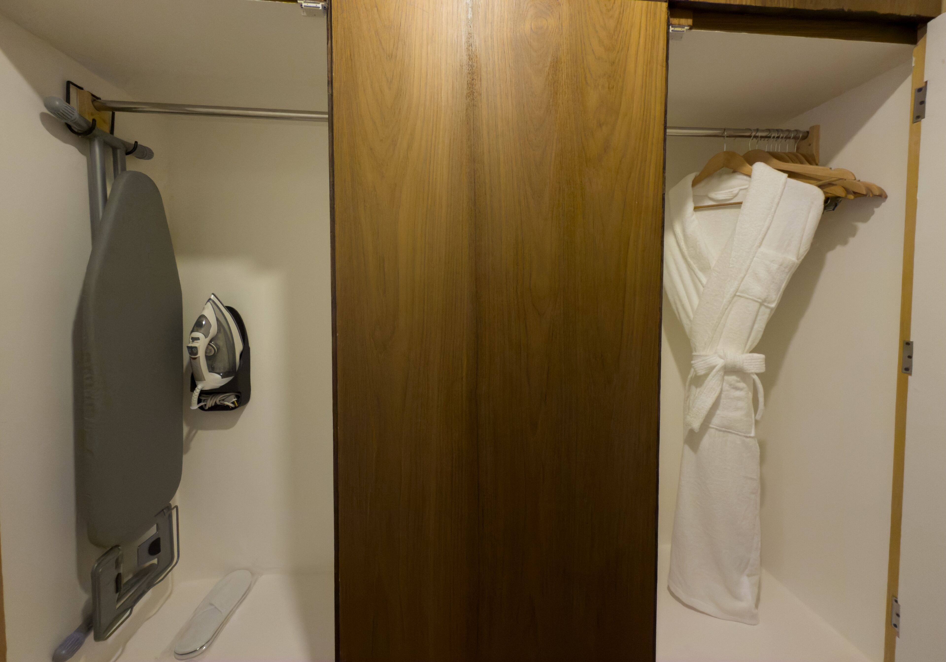Un baño con puerta de madera, un perchero con toalla y un planchador.