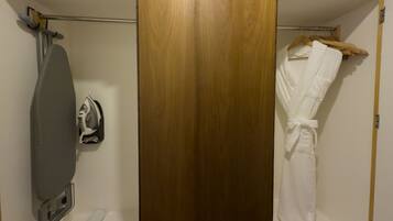 Un baño con puerta de madera, un perchero con toalla y un planchador.