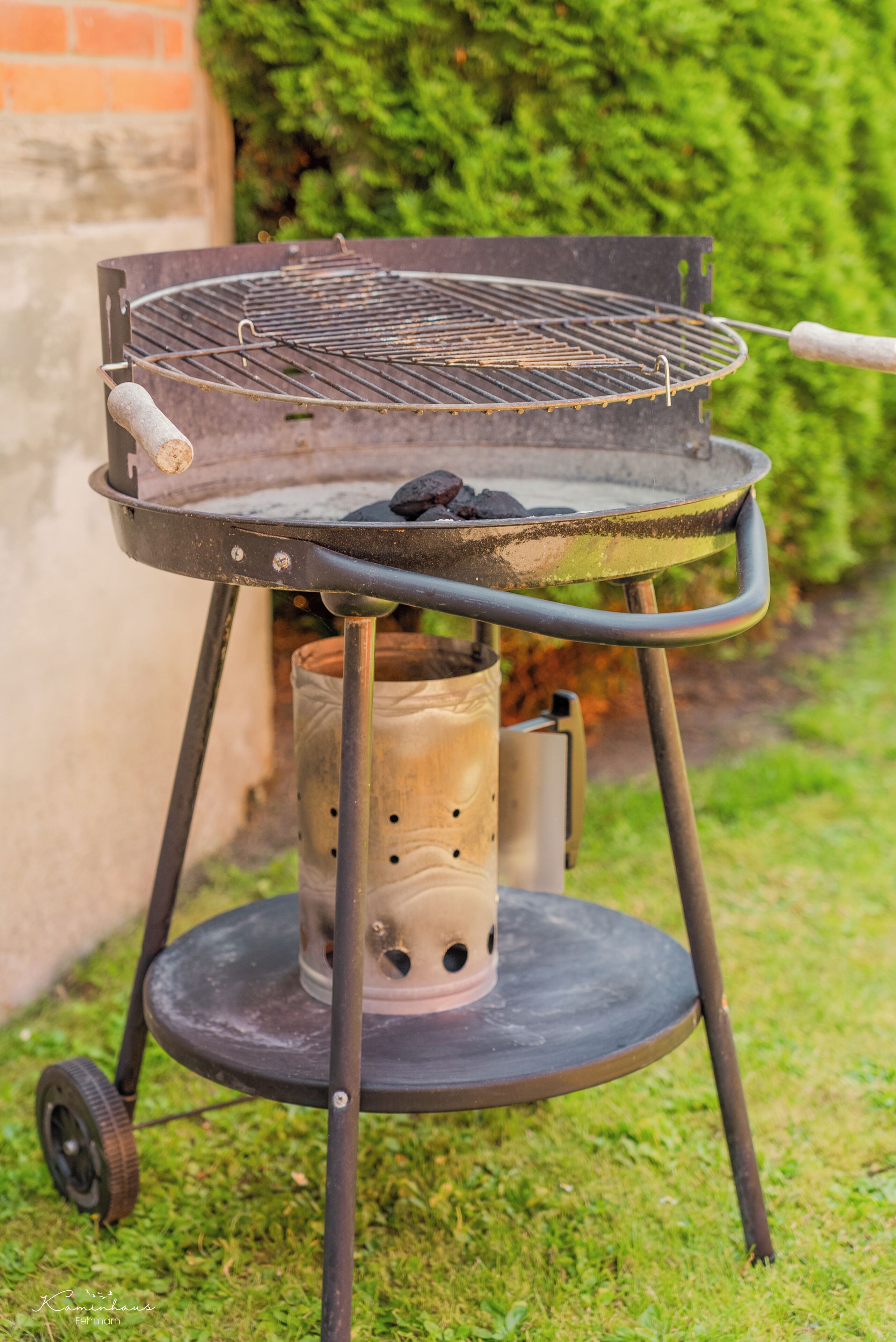 Un barbecue portable doté d’une grille en métal, d’une poignée et d’un réservoir de combustible cylindrique.
