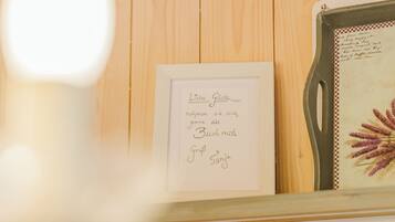 A framed sign with text in a foreign language, a decorative tray with a floral design, and a wooden wall background.