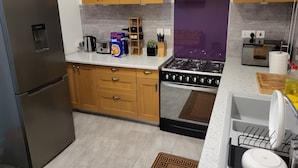 Une cuisine avec des meubles en bois, un réfrigérateur en acier inoxydable, une cuisinière à gaz et un grille-pain.
