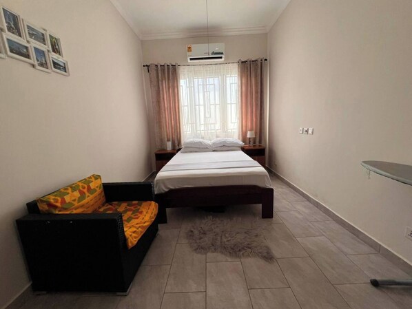 Une chambre à coucher avec un lit, une table de chevet, un canapé et un tapis.